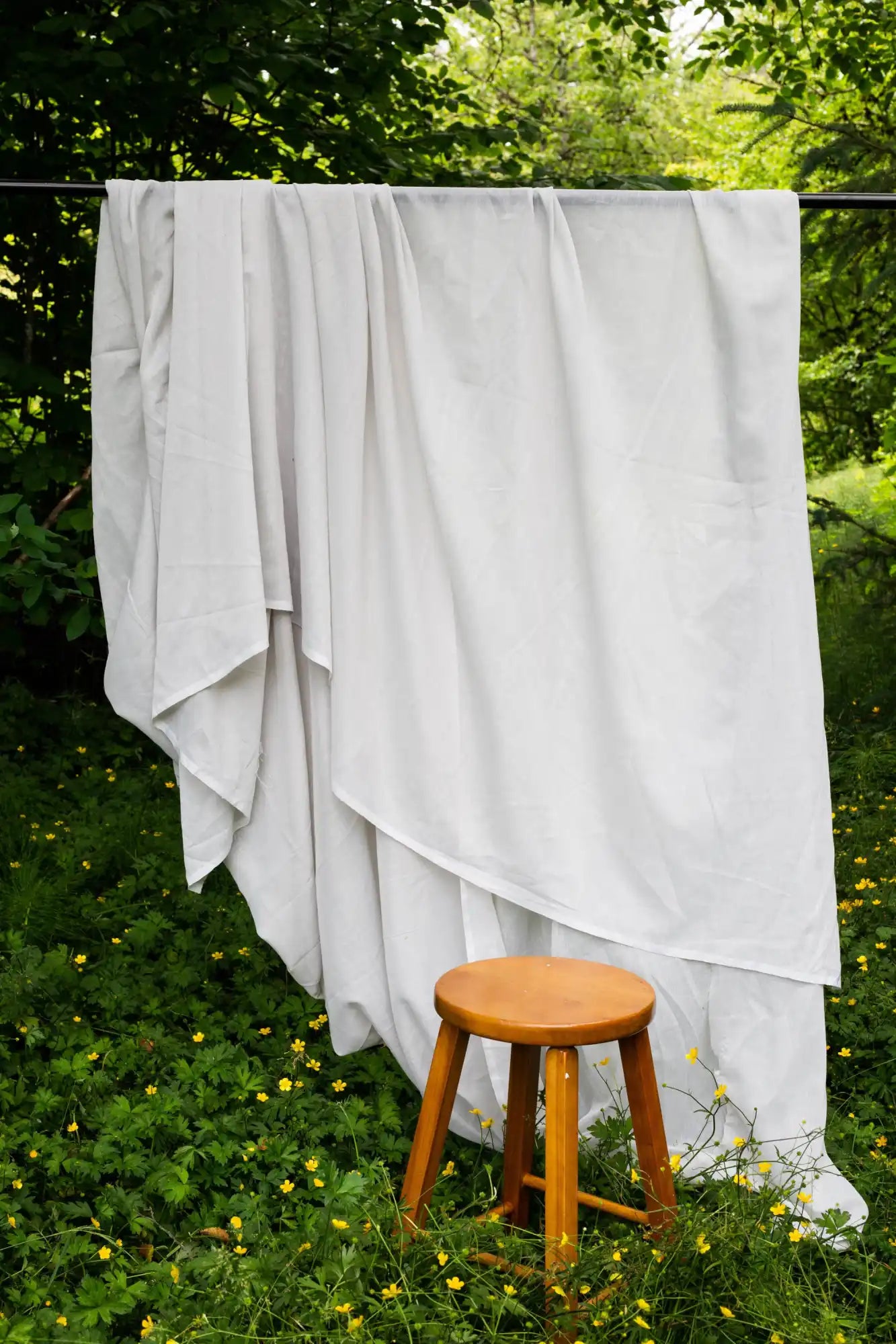Tissu blanc suspendu au-dessus d'une barre avec un tabouret en bois.